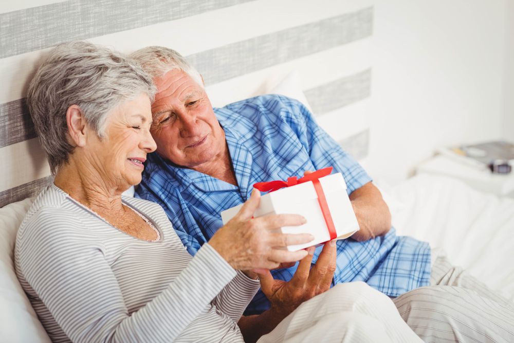 Senior couple looking at gift box in bed