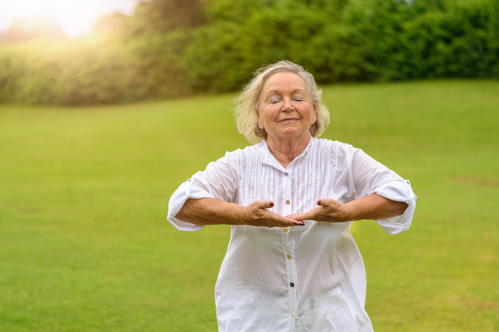 Elderly woman doing breathing exercises outdoors