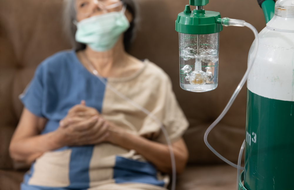 Elderly woman on couch with oxygen tube connected to tank