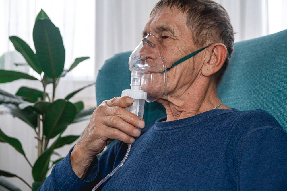 Elderly man in armchair with oxygen mask on