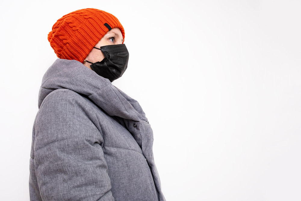 Woman in winter clothing wearing black face mask