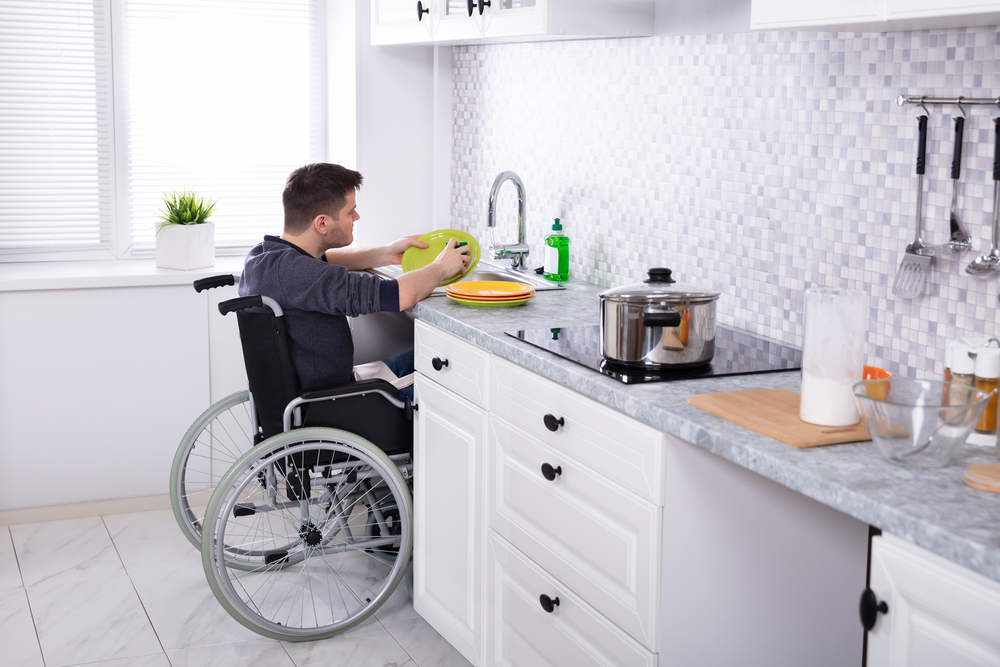 Handicapped man washing dishes in wheelchair-accessible-kitchen